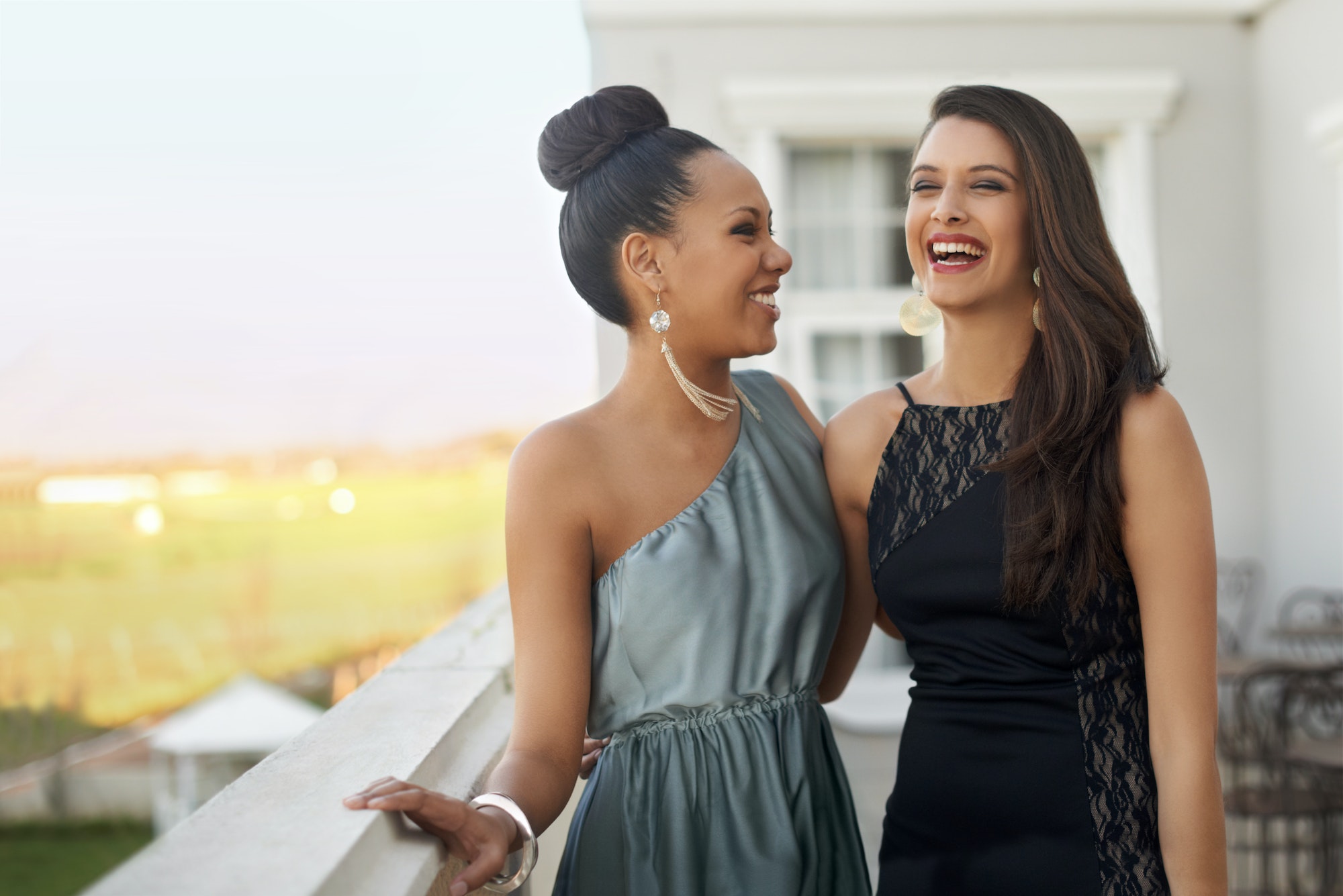 Excitement before the prom. Two young women in evening wear standing on a balcony.